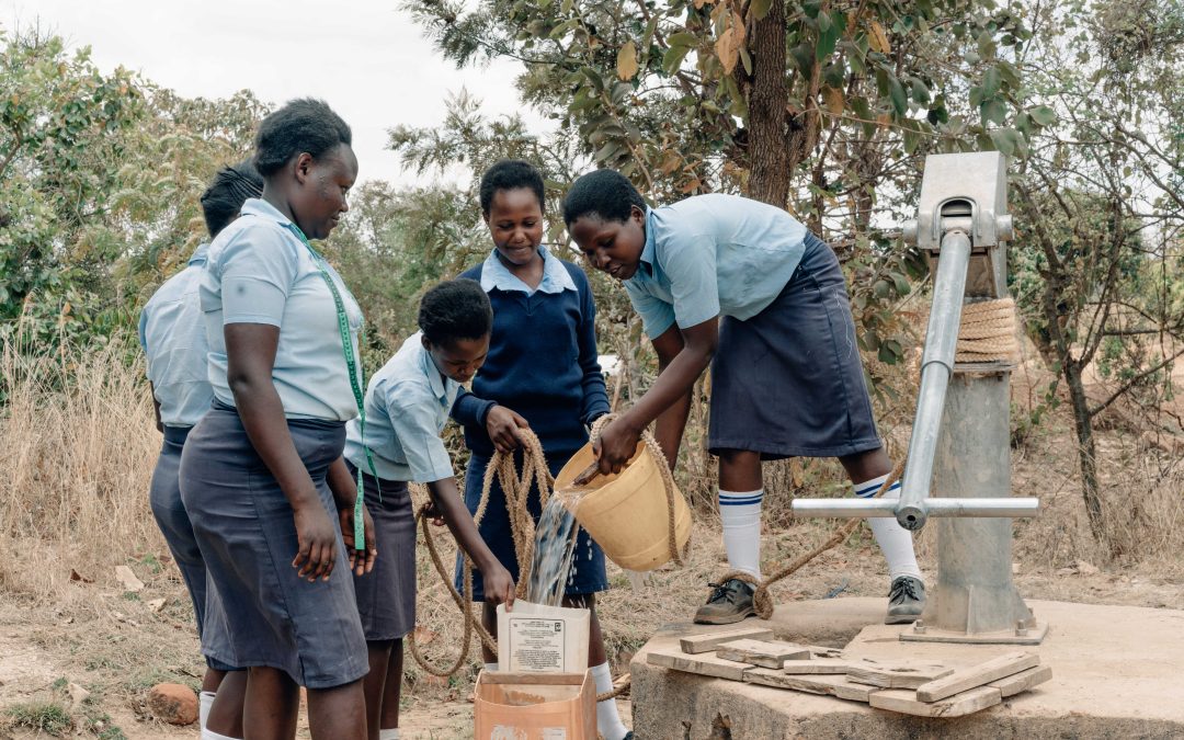 Students collecting water from a well